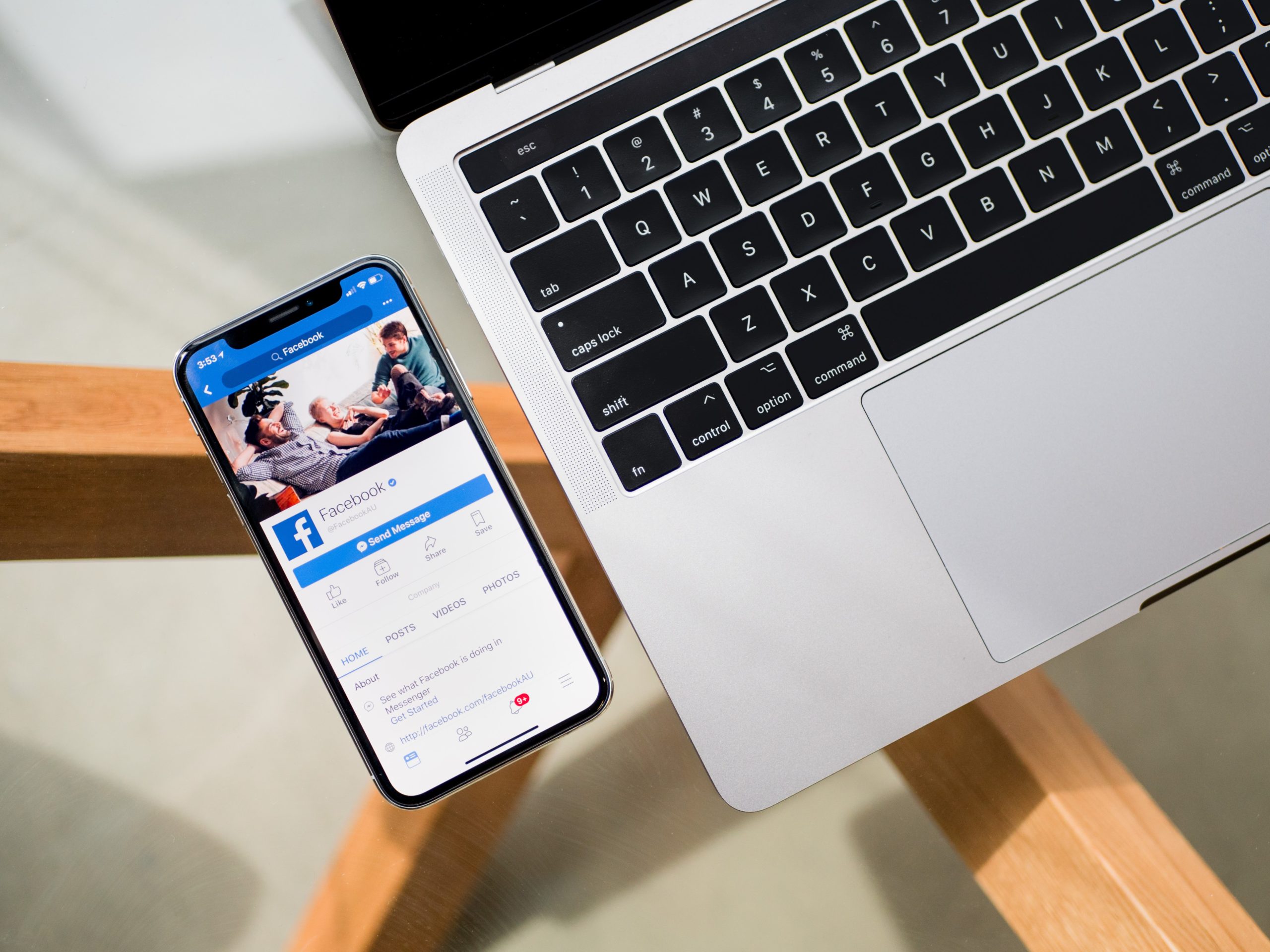 A laptop and a phone next to it showing facebook on the phone screen